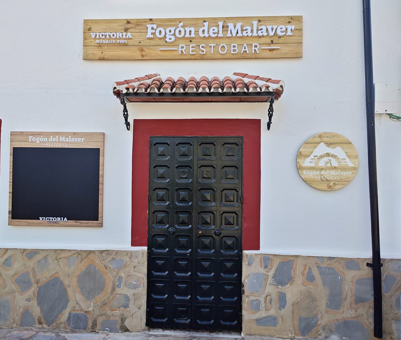 Fachada blanca del Fogón del Malaver con el rótulo sobre la puerta
